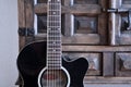 Black acoustic guitar in front of vintage wooden cupboard. Royalty Free Stock Photo