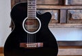 Black acoustic guitar in front of vintage wooden cupboard. Royalty Free Stock Photo