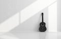 Black acoustic guitar in a white room Royalty Free Stock Photo