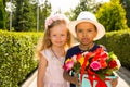 Black african american boy kid gives flowers to girl child on birthday. Little adorable children in park. Childhood and love.