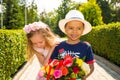 Black african american boy kid gives flowers to girl child on birthday. Little adorable children in park. Childhood and love.