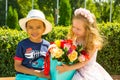 Black african american boy kid gives flowers to girl child on birthday. Little adorable children in park. Childhood and love. Royalty Free Stock Photo
