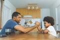 Black African American father competing in arm wrestling with his little boy