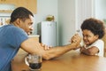 Black African American father competing in arm wrestling with his little boy