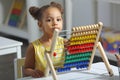 A Black African-American girl is ready for a math and arithmetic lesson with an abacus. Royalty Free Stock Photo