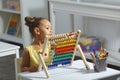 A Black African-American girl is ready for a math and arithmetic lesson with an abacus. Royalty Free Stock Photo