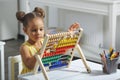 A Black African-American girl is ready for a math and arithmetic lesson with an abacus. Royalty Free Stock Photo