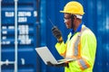 Black African happy worker working in logistic communication using radio and laptop to control loading containers at port cargo to