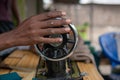 Black African Man hand holding a rotating wheel of the sewing machine in the Village Open Air