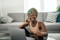 Black African traditional woman working from home wearing head tie scarf Royalty Free Stock Photo