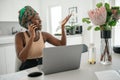 Black African traditional woman working from home wearing headscarf, smiling on phone call Royalty Free Stock Photo