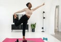 Black African woman one leg yoga standing pose, stretching, home exercise