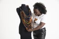 Black African woman working arranging necklaces on a tailors dummy.