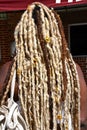 Black Afro-American girl displays a modern hairstyle of woven white braids.
