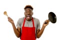 Black afro american man home cook in chef apron cooking pan and spoon lost and overworked Royalty Free Stock Photo