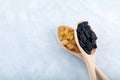 Black ahd yellow seedless raisins in wooden spoons on grey background, close-up. Selective focus, copy space. Dried dehydrated Royalty Free Stock Photo