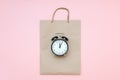 Black alarm clock on craft package on a pink background. Concept Black friday , season sales time. Flat lay Top view Copy space