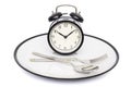 Black alarm clock with fork and knife on the plate. Isolated on white. Time to eat. Weight loss or diet concept Royalty Free Stock Photo