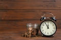 Black alarm clock, glass jar and coins on table against background, space for text. Money savings Royalty Free Stock Photo