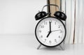 Black alarm clock next to the books on the white table Royalty Free Stock Photo