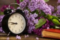 Black alarm clock, an old book and lilac flowers Royalty Free Stock Photo