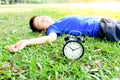 Black alarm clock and sleeping boy in the park Royalty Free Stock Photo