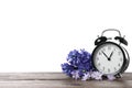 Black alarm clock and spring flowers on table against white background, space for text. Time change