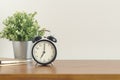 Black alarm clock on wooden desk on white background