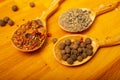 Black allspice, coarse salt and various ground spices in wooden spoons on a wooden Board. Close up