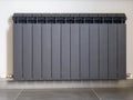 Black aluminum radiator for water heating on the wall in a private house.