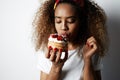 Black american african woman making a mess eating a huge fancy dessert over white background Royalty Free Stock Photo