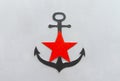 Black anchor with a red star on a gray iron background Royalty Free Stock Photo