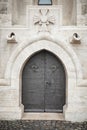 Black ancient metallic door in old stone wall