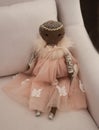 Black angel doll dressed in pink with silver sparkles in a white linen chair