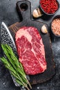 Black angus ribeye, raw rib-eye beef steak on a wooden board with knife. Black background. Top view Royalty Free Stock Photo