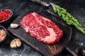 Black angus ribeye, raw rib-eye beef steak on a wooden board with knife. Black background. Top view Royalty Free Stock Photo