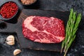 Black angus ribeye, raw rib-eye beef steak on a wooden board with knife. Black background. Top view Royalty Free Stock Photo