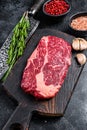 Black angus ribeye, raw rib-eye beef steak on a wooden board with knife. Black background. Top view Royalty Free Stock Photo