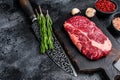 Black angus ribeye, raw rib-eye beef steak on a wooden board with knife. Black background. Top view. Copy space Royalty Free Stock Photo