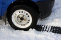 black anti-slip mat of a rectangular shape is placed under the wheel of a low-leveled car after it is stuck in a snowdrift and sli