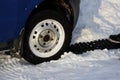 black anti-slip mat of a rectangular shape is placed under the wheel of a low-leveled car after it is stuck in a snowdrift and sli
