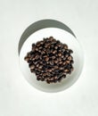 Black arabica fragrant coffee beans on the white plate.