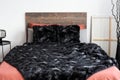 Black artificial fur laying on the coral bedding in the white bedroom