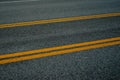 Asphalt road with four yellow lines at diagonal