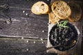 Black Astrakhan Russian salted sturgeon caviar in a can on dark background with wooden spoon and slices of bread. Snacks