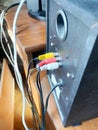 Black audio speaker with RCA input ports and connected cables on a wooden surface, additional electronic devices partially visible Royalty Free Stock Photo