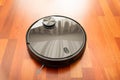 Black automatic vacuum cleaner robot in a house to clean the floor and help in housework. Smart home technology of the future