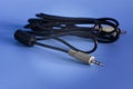 Black aux audio cable on the blue background. Standard 3.5mm Male to Male speaker cable. Use To connect an external audio source Royalty Free Stock Photo