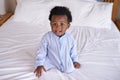 Black baby boy with tongue out in bedroom, sitting on the bed with early childhood development. African male toddler Royalty Free Stock Photo