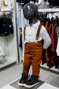 A black baby mannequin in a shirt, suspender pants, and black shoes in a shopping center. Children`s casual clothing store. Moder Royalty Free Stock Photo